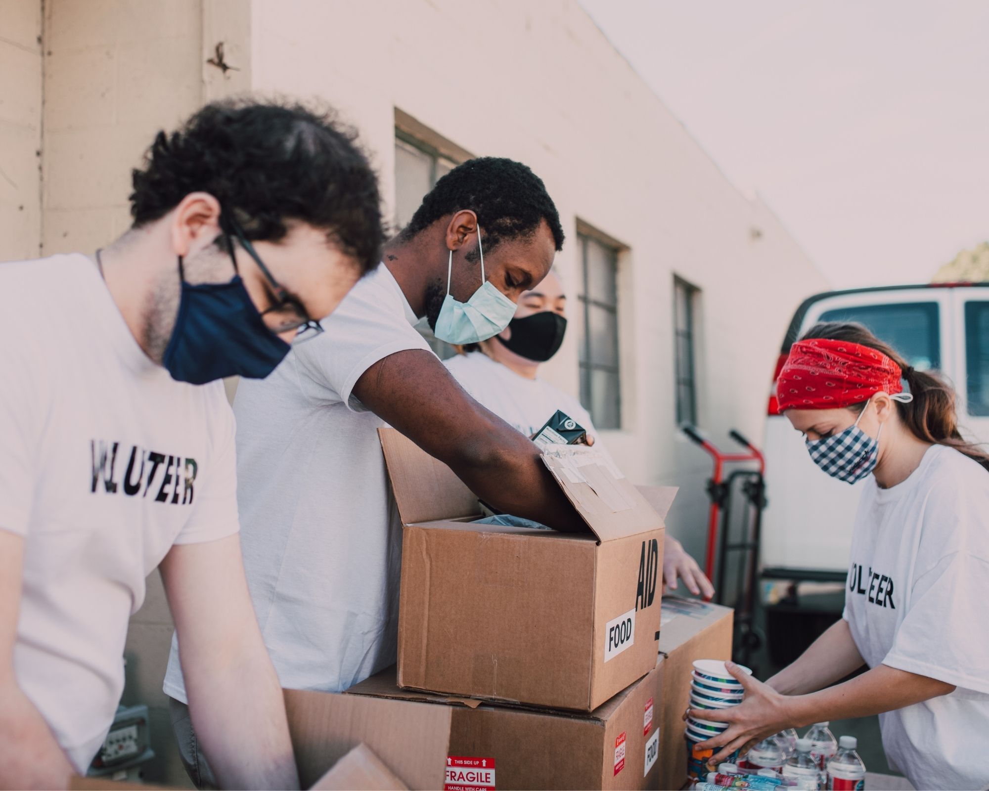 Four donation workers load boxes with items.