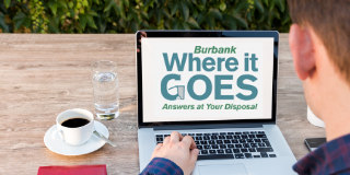 A man uses a laptop computer while eating breakfast, "Burbank - Where it goes - Answers at Your Disposal" is on the screen.