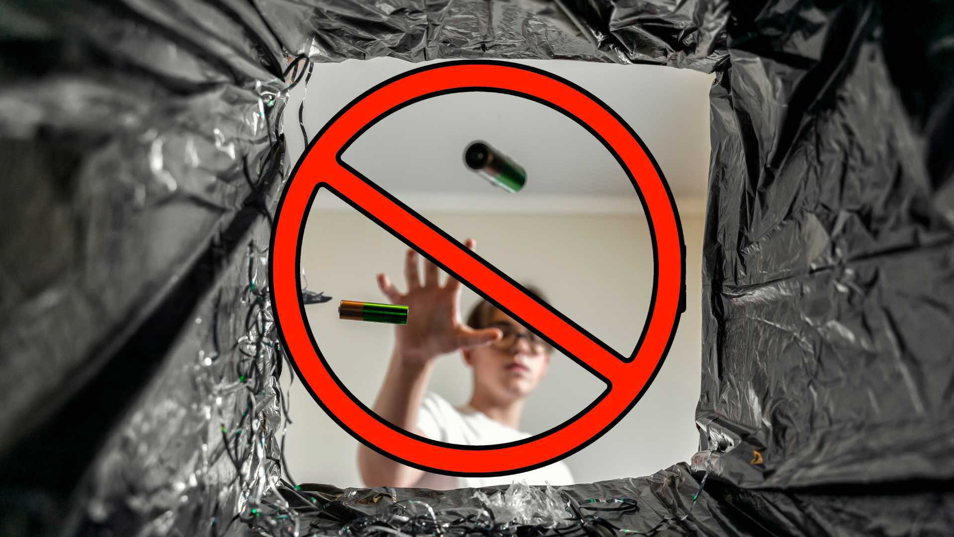 A young male throwing two AA batteries away from the perspective of the trash can. A red prohibition sign is displayed over the act.